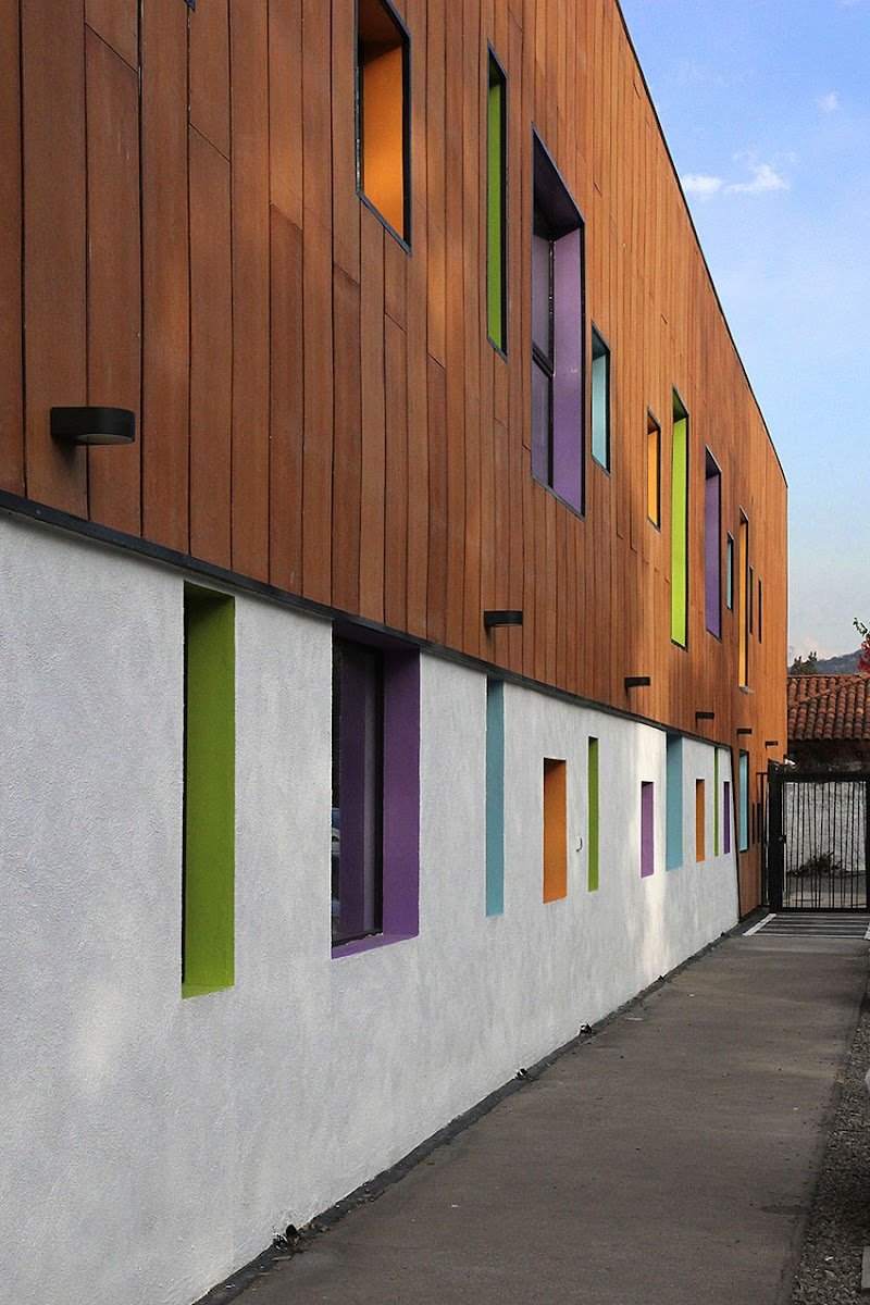 Fachada de madera con ventanas verticales de colores