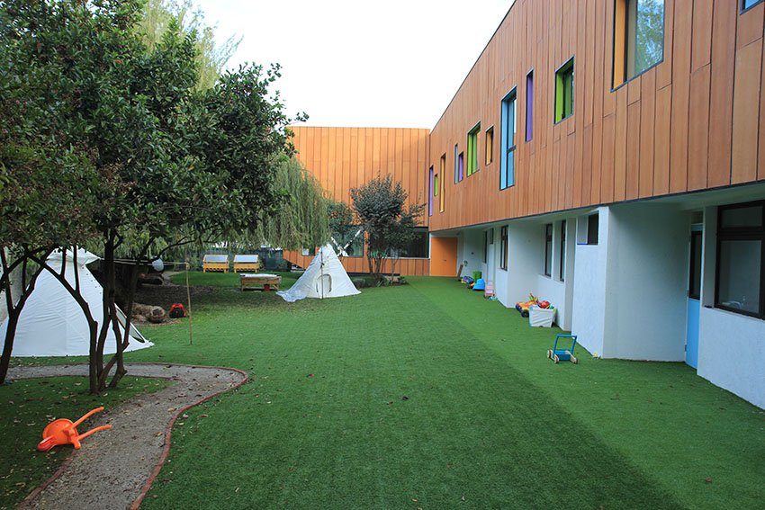 Patio exterior con pasto sintético y áreas verdes